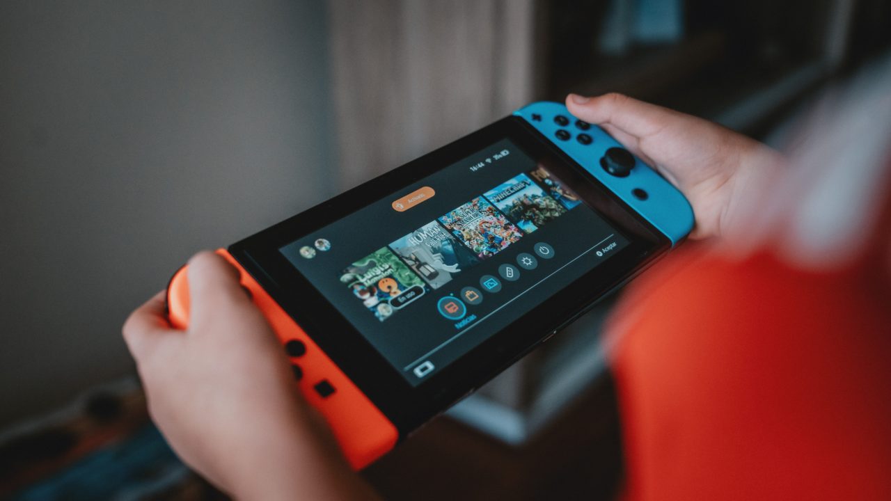 Une personne tient une console Nintendo Switch dans ses mains.