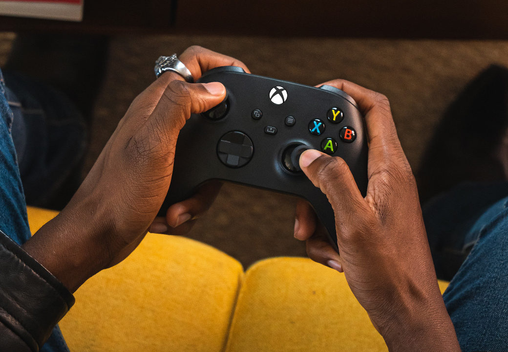 La manette Xbox sans fil, en coloris noir, est tenue dans les mains d'une personne.