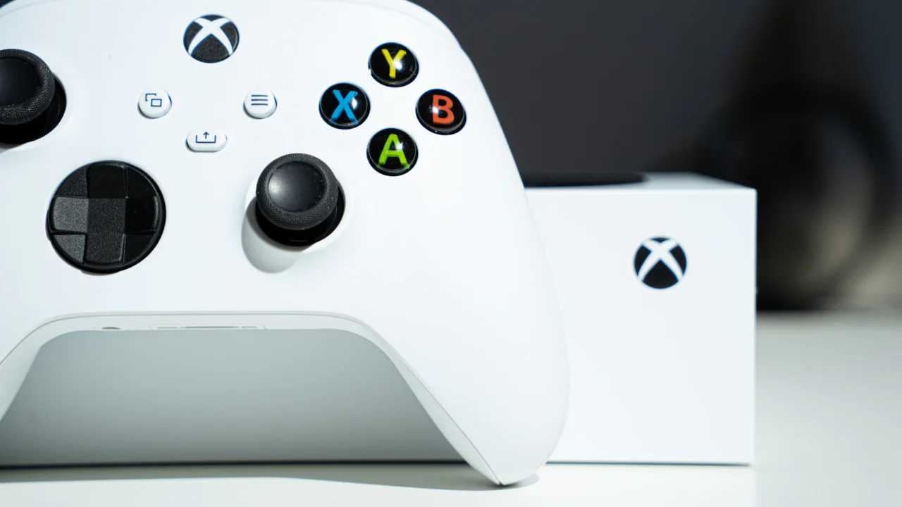 Photo montrant la console Xbox Series S blanche posée derrière une manette sans-fil blanche de Xbox